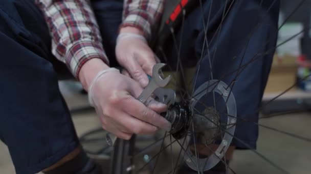Веломеханическое закрепление велосипедного колеса в ремонтной мастерской. Сервис велосипеда. Ремонтник мужского велосипедного магазина ремонтирует велосипедное колесо в мастерской. Техник чинит детали для велосипедов. Разнорабочий на рабочем месте - Кадры, видео
