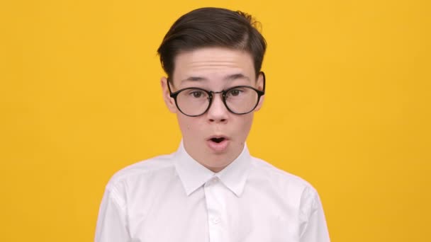 Schockierter Teenie-Junge blickt auf Kamera, die Gesicht berührt, gelber Hintergrund - Filmmaterial, Video