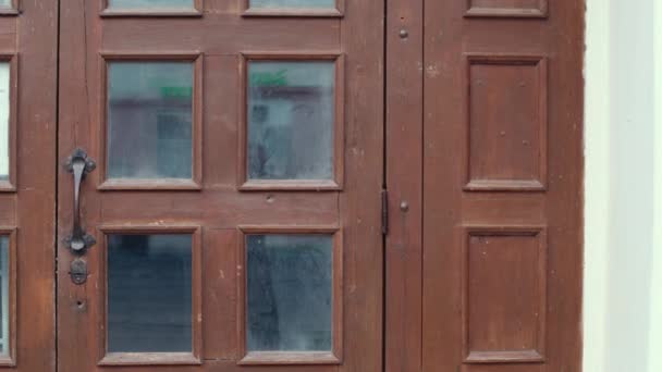 Μια παλιά κόκκινη πόρτα με μια παλιά σκουριασμένη λαβή πόρτας και βρώμικα παράθυρα - Πλάνα, βίντεο