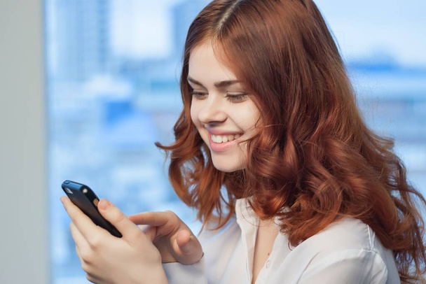 hezká žena v košili s telefonem v ruce komunikace kancelář profesionální - Fotografie, Obrázek