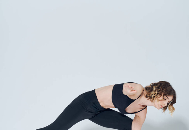 Une femme sur un fond clair fait des exercices une silhouette mince de yoga asana - Photo, image