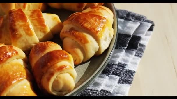 Kotitekoinen herkullisia croissanteja jälkiruoka harmaa levy keittiön pyyhe pyörii. Maukas kotitekoinen croissants kakku - Materiaali, video