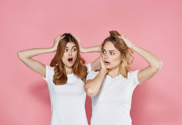 dwie emocjonalne dziewczyny w t-shirt zabawy styl życia studio różowy tło - Zdjęcie, obraz