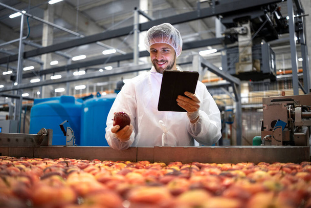 Teknoloji uzmanı gıda işleme tesisinde elma meyvesi üretiminin kalite kontrolünü yapıyor. - Fotoğraf, Görsel