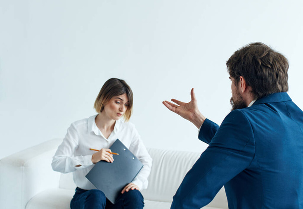 Homme d'affaires en costume classique et une femme sur le canapé avec des documents dans les mains d'un psychologue  - Photo, image