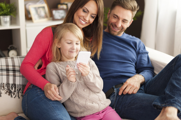 Девушка с родителями играет по мобильному телефону
 - Фото, изображение