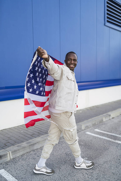 A vertical shot of a black male holding the flag of the USA - Fotografie, Obrázek