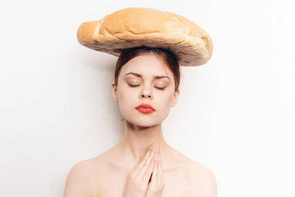 boldog nő egy kenyérrel a fején gesztikulál a kezével meditáció és smink modell - Fotó, kép