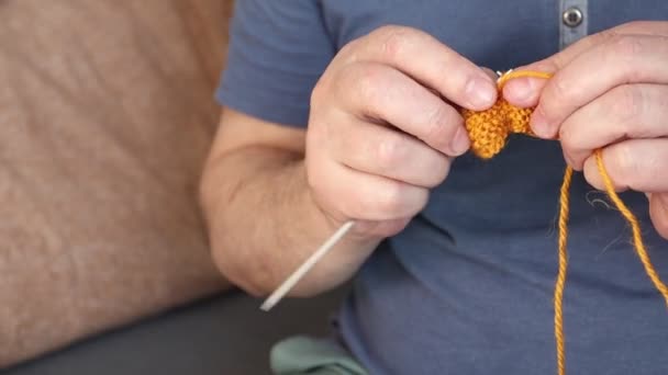 オレンジの糸でスカーフを編む男。自宅で手作り - 映像、動画
