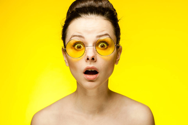 Çekici, esmer, sarı gözlüklü, çıplak omuzlu stüdyo. - Fotoğraf, Görsel