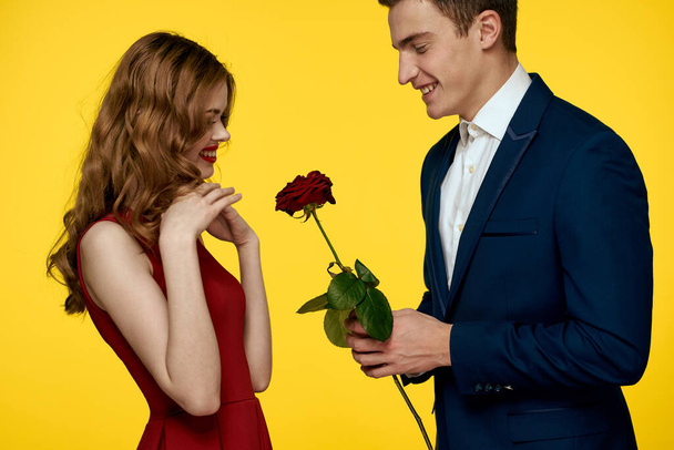man en vrouw date roos luxe gele achtergrond - Foto, afbeelding