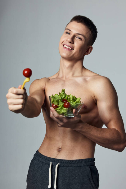 Neşeli sporcu adam, şişirilmiş karın kasları, tabak salatası, sağlıklı yemek ve manzara. - Fotoğraf, Görsel