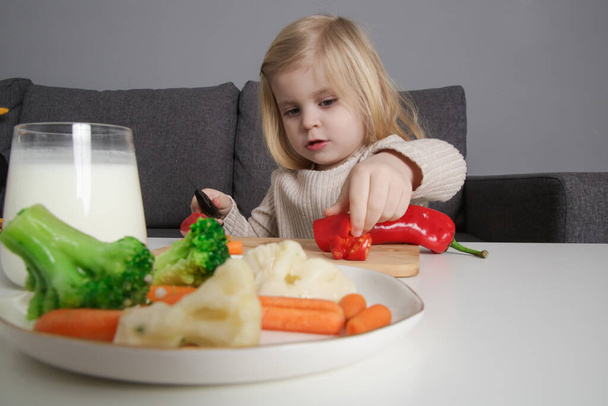Портрет чарівної дівчинки-малятка, яка готує здорову їжу, ріже овочі ножем
. - Фото, зображення