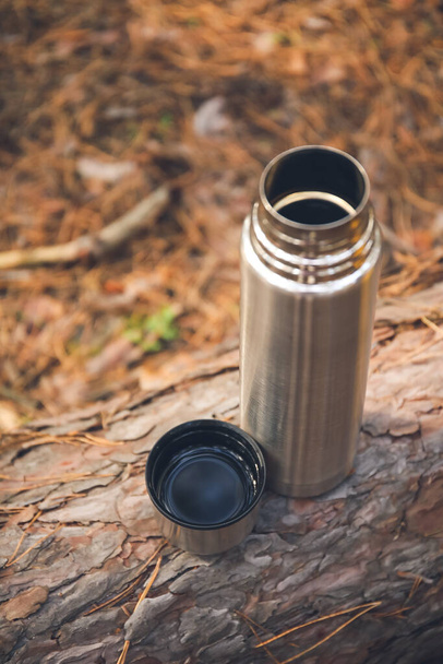 Thermos with hot tea in forest - Photo, Image