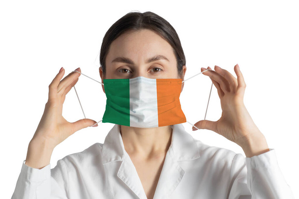 Респіратор з прапором Ірландії Доктор ставить медичну маску ізольовану на білому тлі. - Фото, зображення