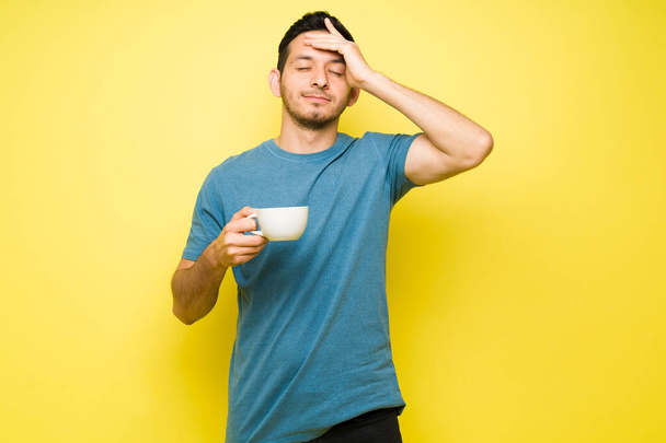 Lateinischer Mann, der Kopfschmerzen hat, weil er noch keinen Kaffee getrunken hat. Hispanischer Mann in seinen Dreißigern mit Migräne nach Koffeinkonsum - Foto, Bild