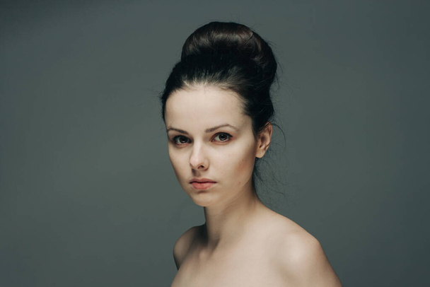 красивая женщина с голыми плечами на сером фоне модель прически - Фото, изображение