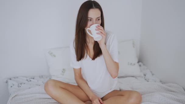 Spokojny inspirowane kobieta mając gorący napój na łóżku rano - Materiał filmowy, wideo