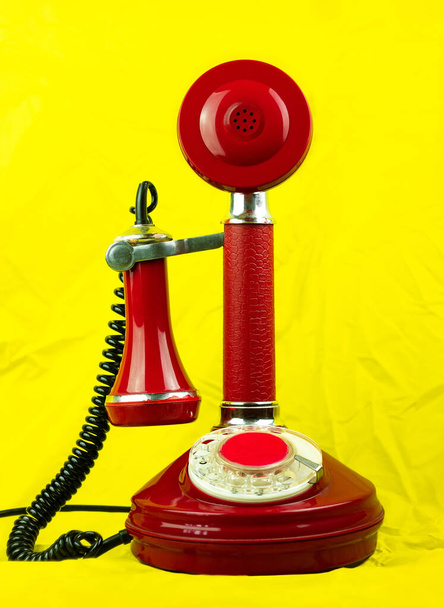 Red retro phone on yellow background. Vintage telephone device on bright modern pastel color fabric surface. Nostalgia concept. conversation connection technology support service old-fashioned symbol. - Photo, Image