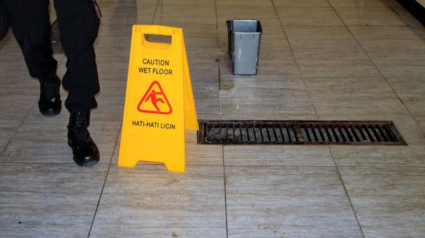  A padló csúszós, miután felmosták, megjelölve egy táblával: Vigyázat, nedves padló. - Fotó, kép
