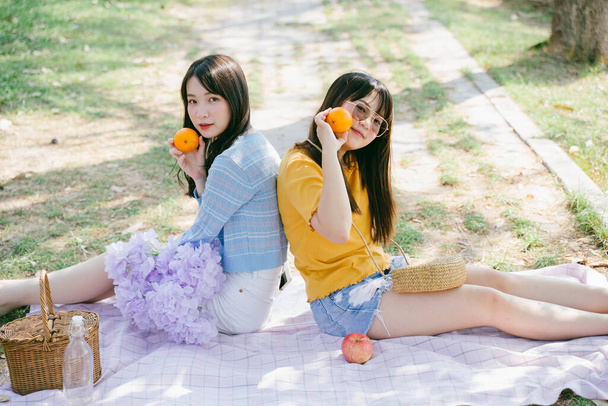 Két lány ül a lábtörlőn a földön a narancsot tartva és játszanak.. - Fotó, kép