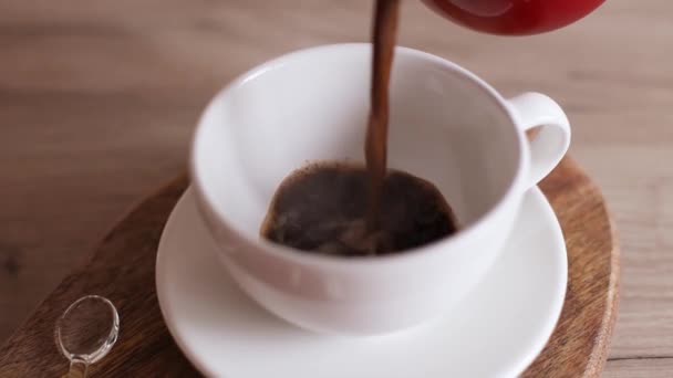 Mano femminile versando caffè espresso in tazza di ceramica in cucina. Caffè Jezve utilizzando caffettiera turca - Filmati, video