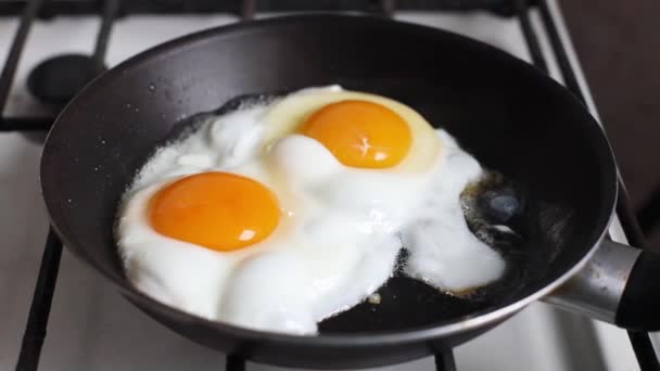 Close-up de ovos fritos na frigideira preta. Conceito de pequeno almoço. - Filmagem, Vídeo