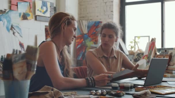 Sanat stüdyosunda genç bir sanatçıyla resimlerini tartışan kadın müşterinin görüntüsünü yakınlaştır. - Video, Çekim