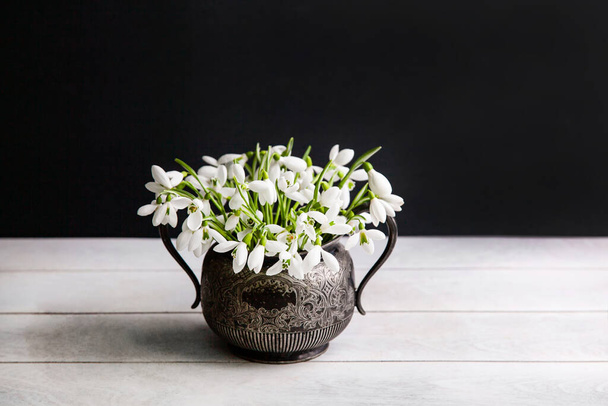 Ramo de nevadas blancas Galanthus nivalis en tarro retro vintage sobre fondo oscuro. - Foto, imagen