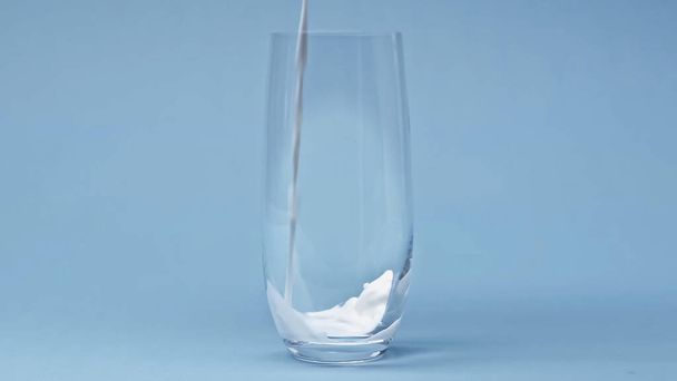 latte fresco versato in vetro su fondo blu - Foto, immagini