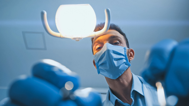 bottom view of dentist in latex gloves working in clinic, blurred foreground - Photo, Image
