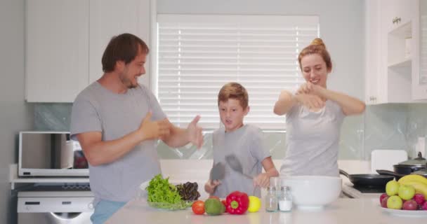 Famille heureuse drôle et enfants mignons s'amusant à danser dans la cuisine ensemble, maman active papa appréciant la danse funky avec son fils. - Séquence, vidéo