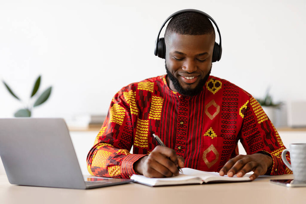 Etnik Gömlekli ve Kulaklıklı Bilgisayarlı Afro-Amerikan Olumlu Adam - Fotoğraf, Görsel