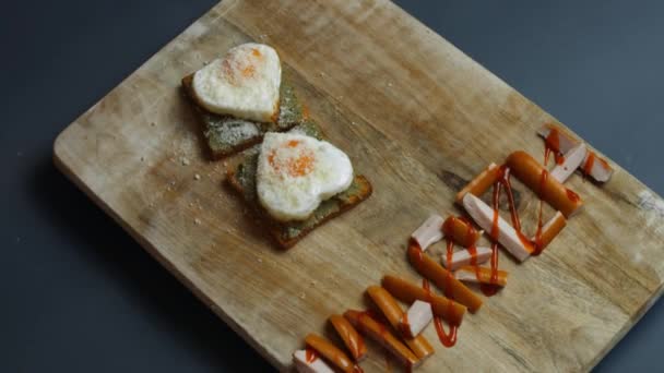 Wortmarsch aus saftigen Fleischwurstscheiben mit Tomatensauce. Serviert mit herzförmigen Eiern auf Toastbrot mit zertrümmerter Avocado und Parmesankäse. Kochen eines Überraschungsfrühstücks für den 8. März. Rosa - Filmmaterial, Video