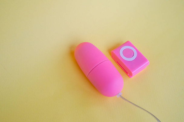 Vibrator egg pink color. Adult sex toy, dildo vibrator for clitoris, on yellow background. - 写真・画像