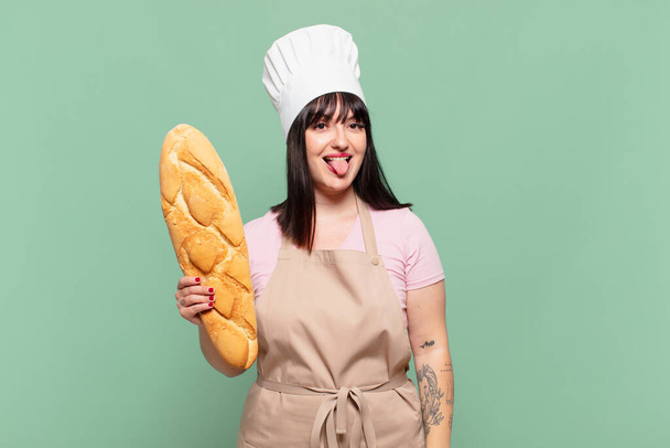 young chef woman with cheerful, carefree, rebellious attitude, joking and sticking tongue out, having fun - Foto, Imagem