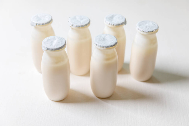 Small bottles with probiotics and prebiotics dairy drink on white background. Production with biologically active additives. Fermentation and diet healthy food. Bio yogurt with useful microorganisms - Photo, Image