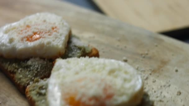 Saftige Fleischwürste schneiden, um sie mit herzförmigen Eiern auf Toasts mit zertrümmerter Avocado und Parmigiano zu servieren. Kochen eines Überraschungsfrühstücks für den 8. März - Filmmaterial, Video