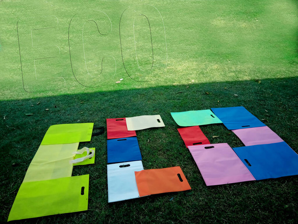 ECO Word Showing met Niet Geweven D-Cut Kleurrijke Tassen geïsoleerd op groen veld. Milieuvriendelijk concept - Foto, afbeelding