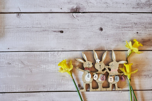 Wooden Easter bunnies with decoration and the text Easter written on eggs. - Photo, Image