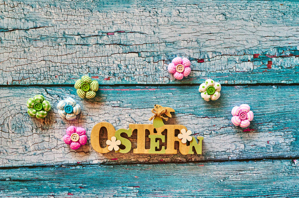 Wooden sign with an Easter bunny with flowers as decoration. The Text is German for Easter. - Photo, Image