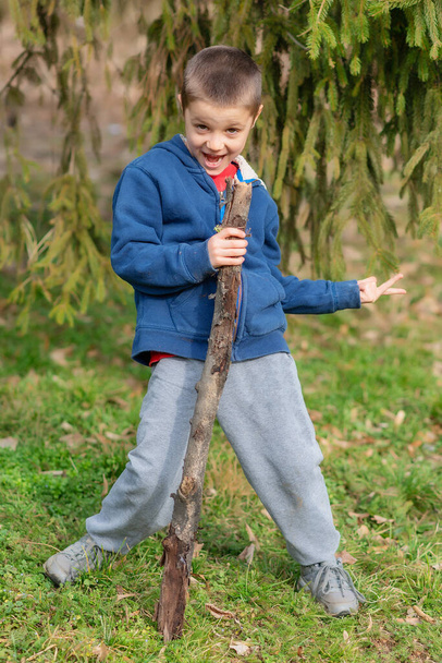Petit garçon jouer avec le bâton dans la forêt. Le garçon chante dans la nature - Photo, image