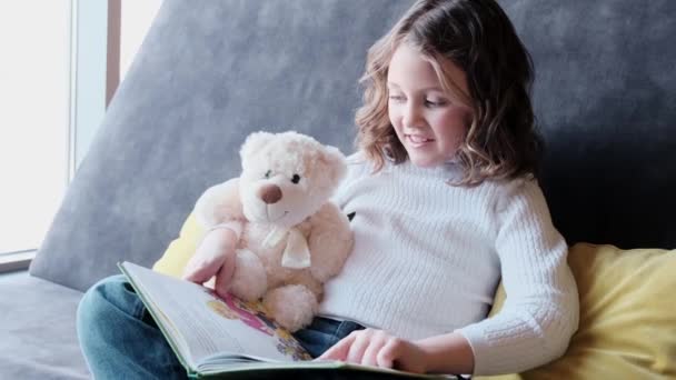 Красивая маленькая девочка читает интересную книгу. - Кадры, видео