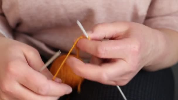 オレンジの糸でスカーフを編む女性。自宅で手作り. - 映像、動画