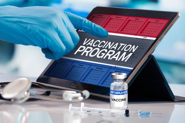 Professional työskentelevät kalenterissa rokotteiden suunnitelma Alankomaiden kansakunta, Immunization käsite. Työskentely tabletin kanssa Alankomaiden rokotusohjelmassa. Fotomontaasi 3D-kuvituksella - Valokuva, kuva