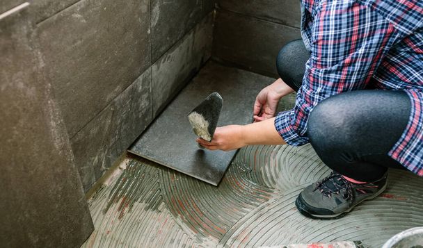 Женщина-ручной рабочий кладет новый пол плитки - Фото, изображение