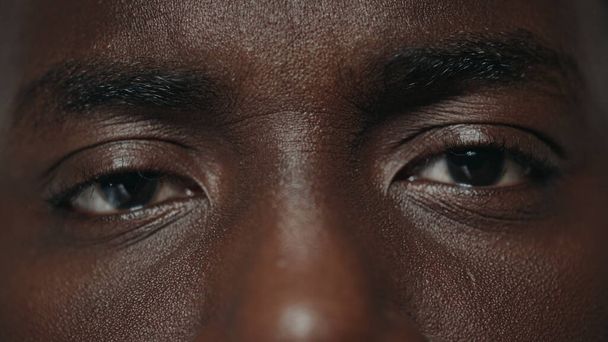 Ekstremalne zbliżenie zaskoczony afrykański amerykański mężczyzna oczy patrząc w aparat.  - Zdjęcie, obraz