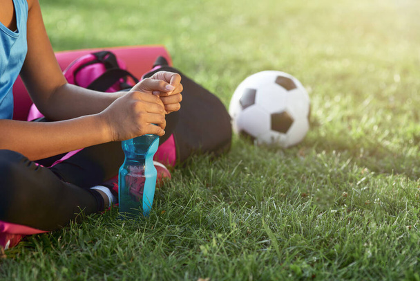 Deportiva niña con botella de agua sentada en la hierba - Foto, Imagen
