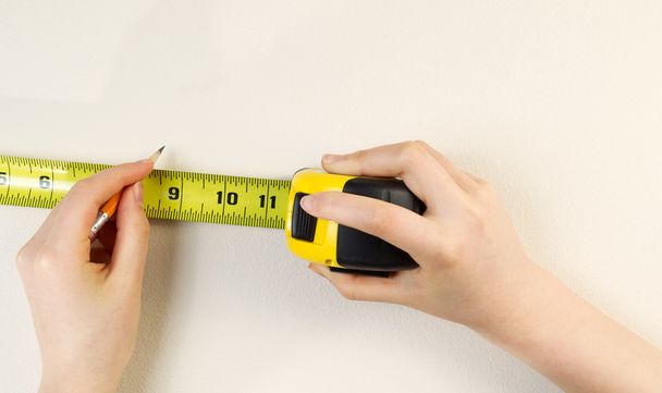 Tape Measure and Pencil preparing to mark interior wall - Photo, Image