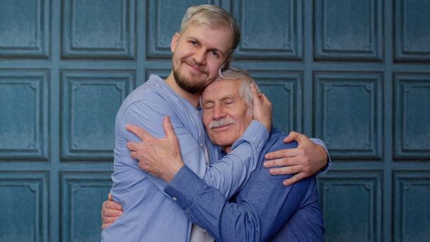 Heureux jeune homme excité embrassant vieux père ou grand-père aux cheveux gris, famille des générations masculines - Photo, image